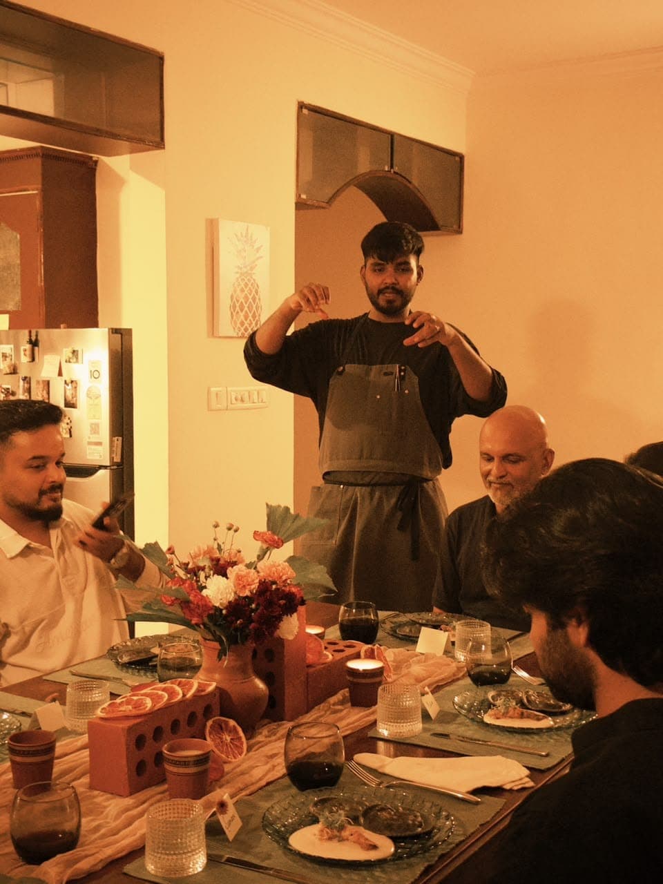 A chef standing at the table, explaining a course to the guests